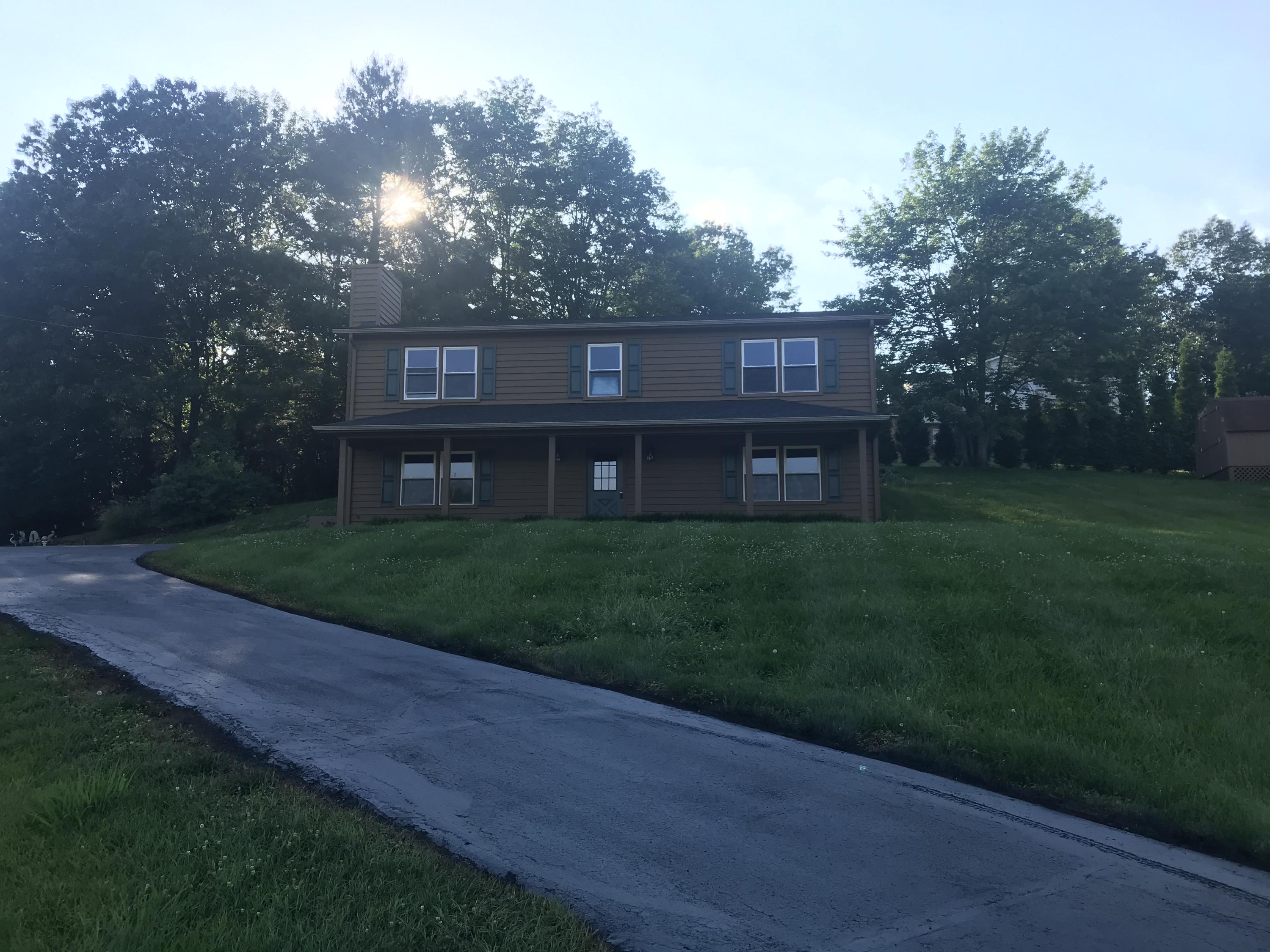 a view of a brick house next to a yard with big trees