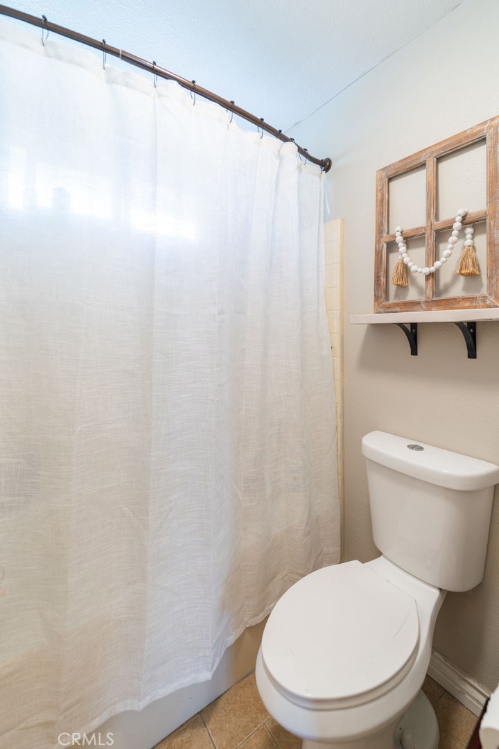 8636 Rancho Cerona Drive Paramount, CA 90723 - Photo 38 of 48 a white toilet sitting next to a shower curtain