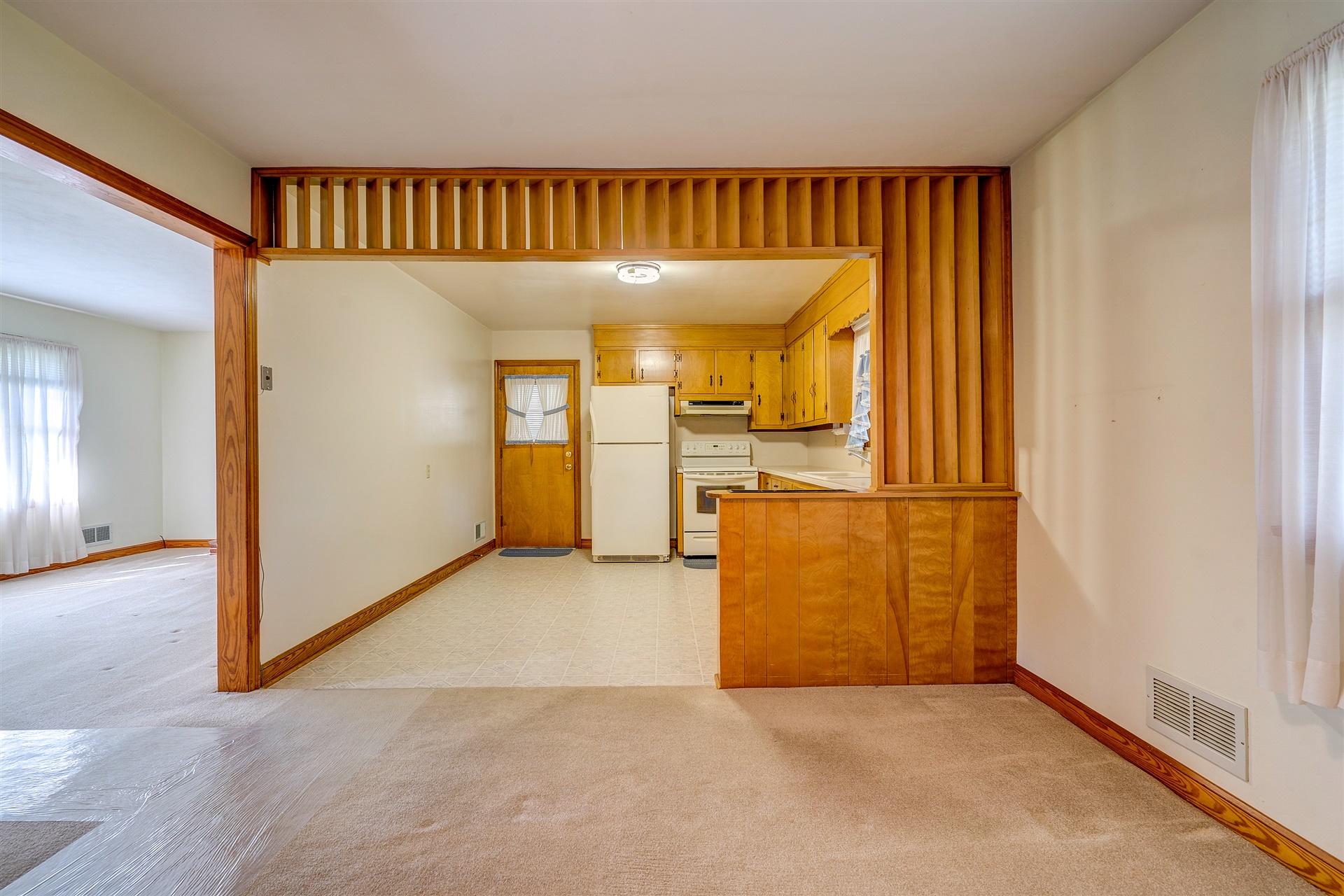 1702 Eanes Road Roanoke, VA 24014 - Photo 5 of 21 an empty room with wooden floor and a kitchen
