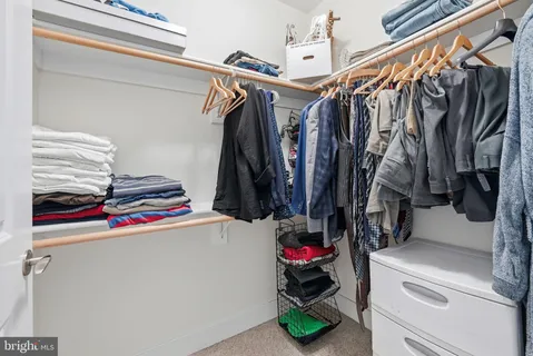 a view of walk in closet with clothes and shoes