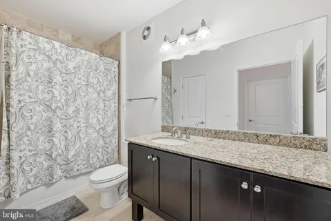 a bathroom with a granite countertop sink a toilet and a mirror