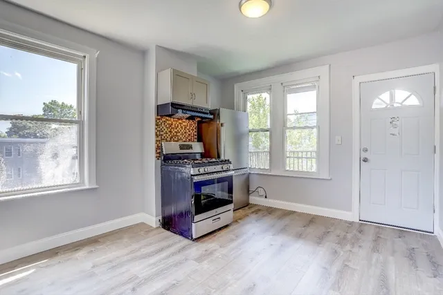 a living room with stainless steel appliances wooden floor and a window