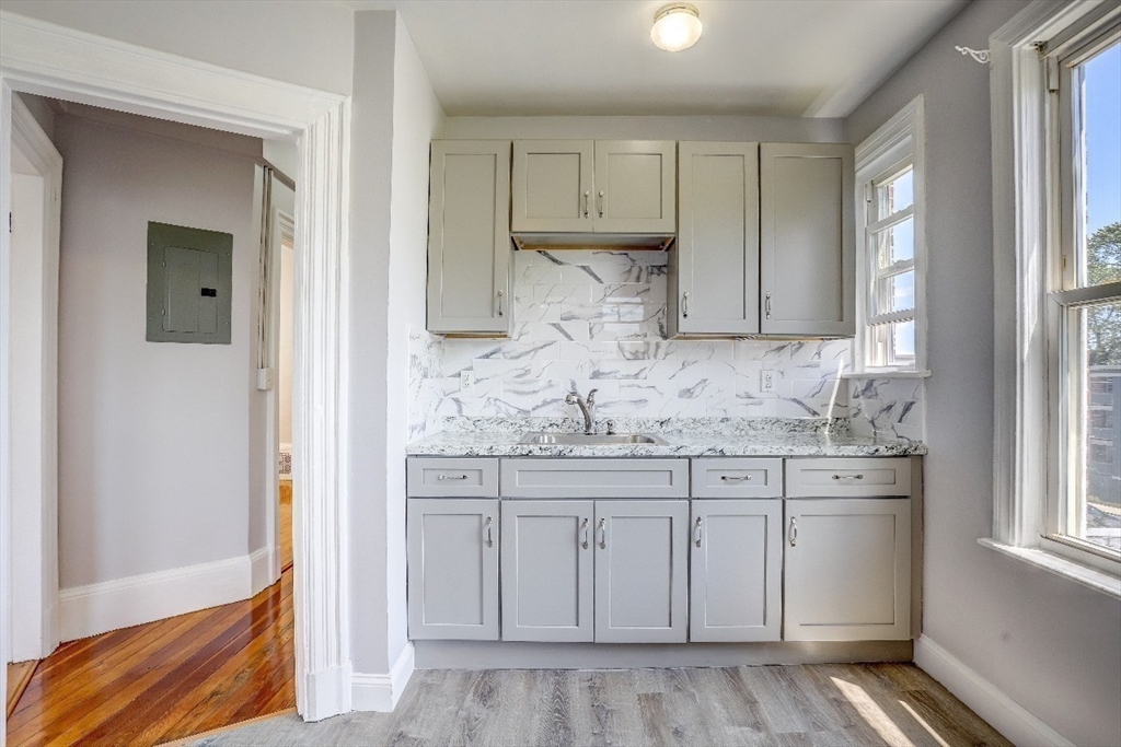 83 Topliff Street, Unit ALL Boston, MA 02122 - Photo 7 of 25 a kitchen with granite countertop white cabinets and white appliances