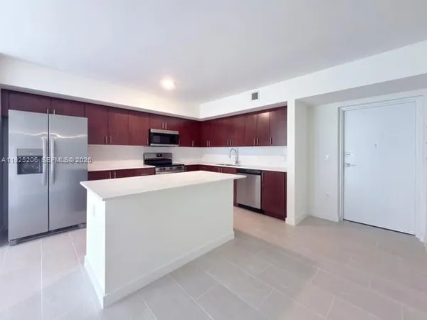 a kitchen with stainless steel appliances a sink a stove a microwave a refrigerator and cabinets