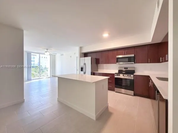 a kitchen with stainless steel appliances kitchen island granite countertop a stove top oven a sink a counter top space and cabinets
