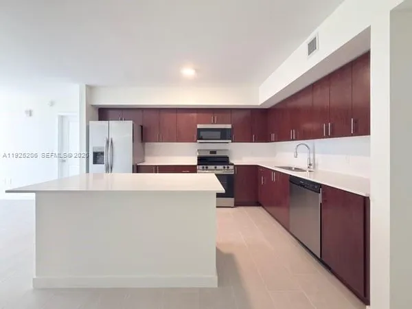 a kitchen with stainless steel appliances kitchen island granite countertop a refrigerator sink and cabinets