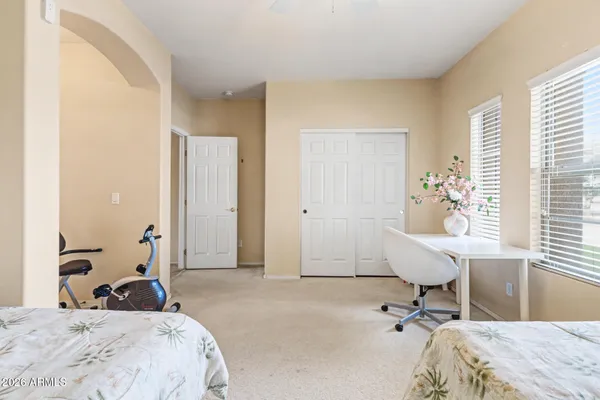 a bedroom with a bed a table and large windows
