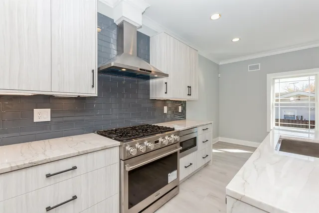 a kitchen with stainless steel appliances granite countertop a stove and a white cabinets