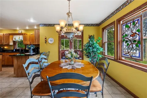 a view of a dining room with furniture a chandelier and large windows