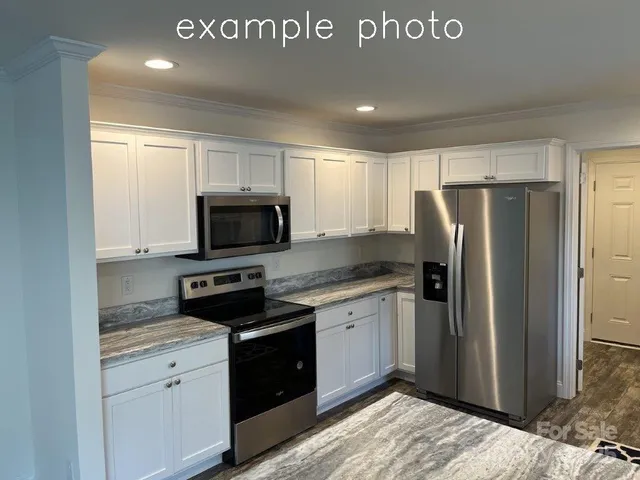 a kitchen with stainless steel appliances granite countertop a refrigerator a stove and a sink with wooden floor