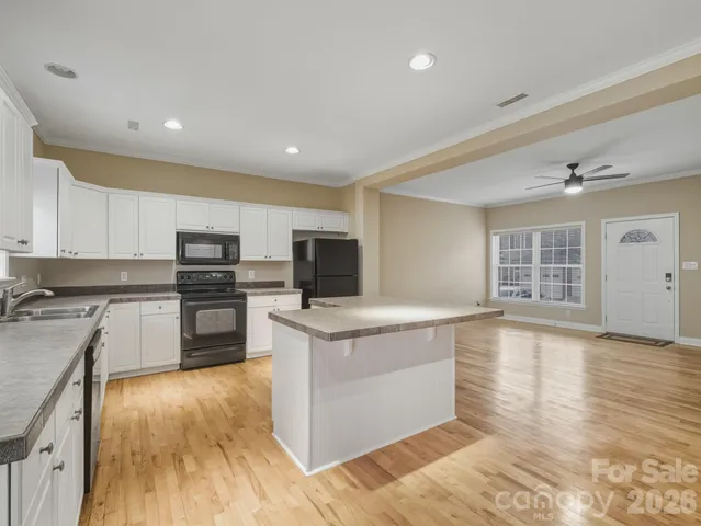 a kitchen with stainless steel appliances kitchen island granite countertop a stove top oven and sink