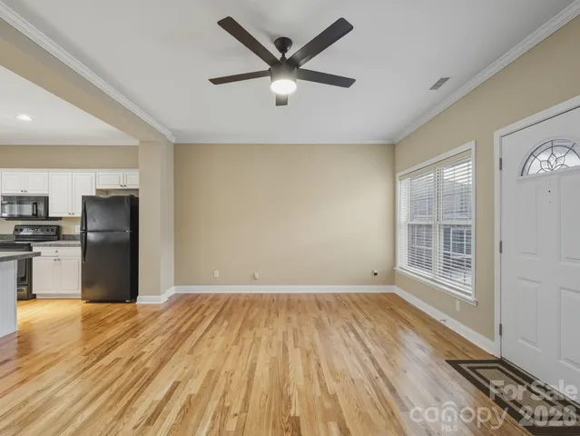 a view of empty room with wooden floor and kitchen view