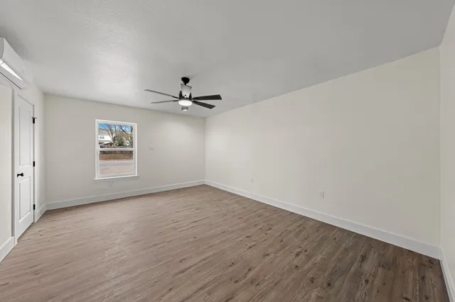a view of an empty room with a window and wooden floor
