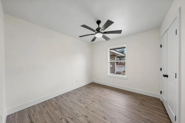 a view of an empty room with a window and wooden floor
