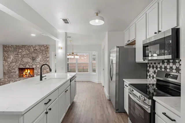 a kitchen with stainless steel appliances a sink cabinets and a wooden floor