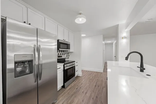 a kitchen with stainless steel appliances granite countertop a refrigerator a sink and wooden floors