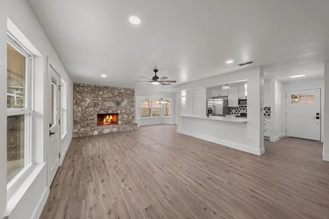 a view of a hallway with wooden floor and a kitchen