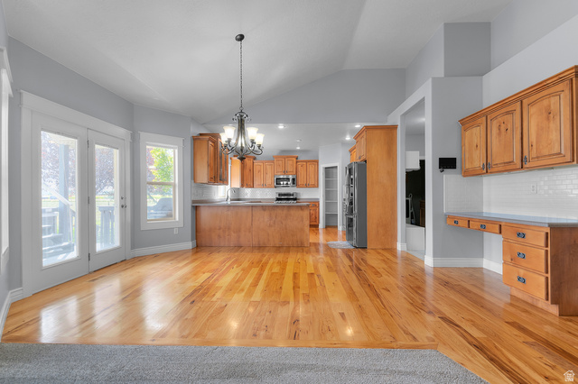 1501 West Elk Circle Mapleton, UT 84664 - Photo 16 of 39 Open-concept living area with vaulted ceilings, wood-finish flooring, and a kitchen featuring wood cabinetry
