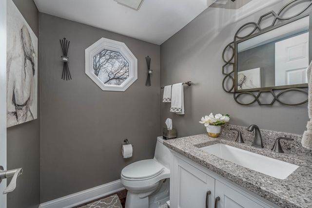 a bathroom with a granite countertop toilet sink and mirror