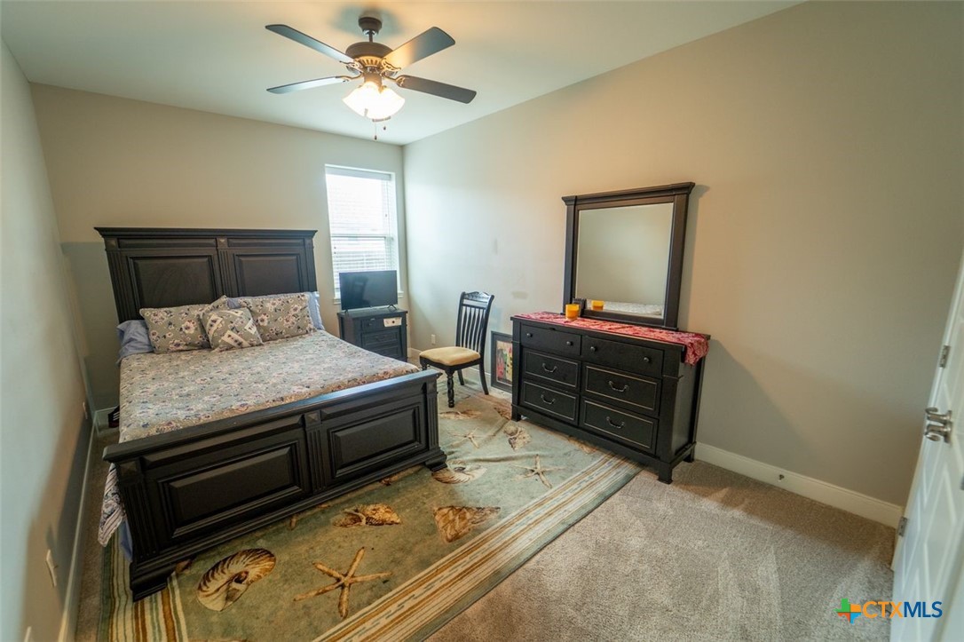 113 Terra Vista Ranch Road Victoria, TX 77904 - Photo 14 of 27 a bedroom with a bed and a chandelier