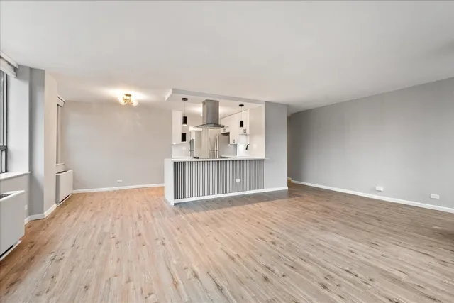 a view of kitchen and empty room with wooden floor