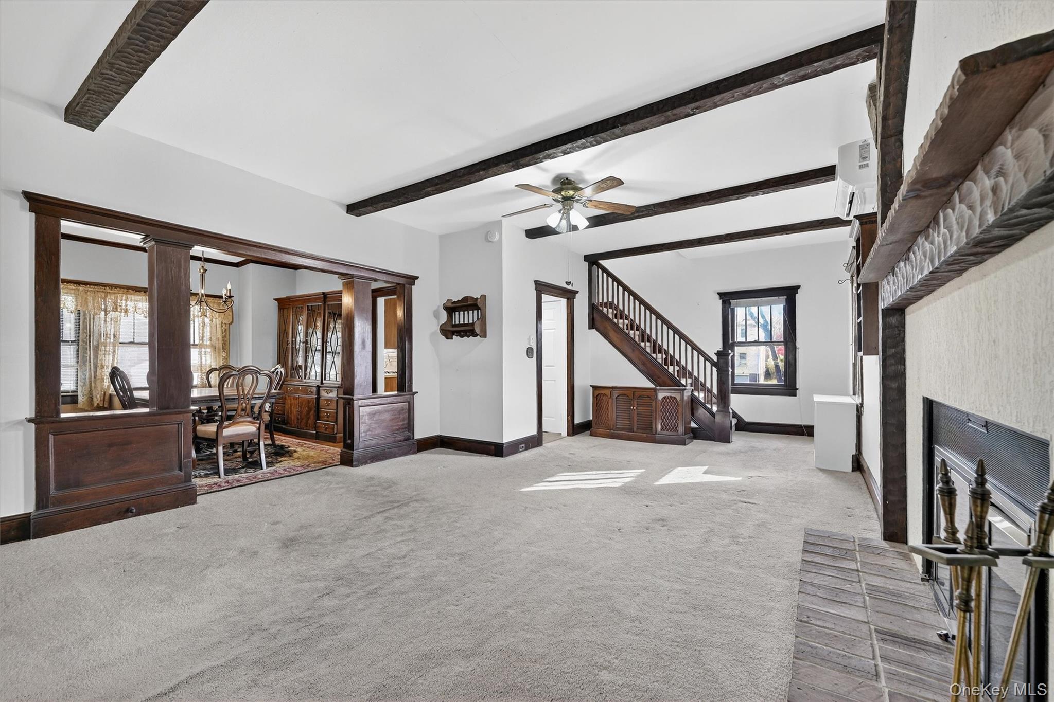 165 Wayne Avenue Suffern, NY 10901 - Photo 12 of 38 Carpeted living room featuring beamed ceiling, a chandelier, an AC wall unit, a ceiling fan, and stairway