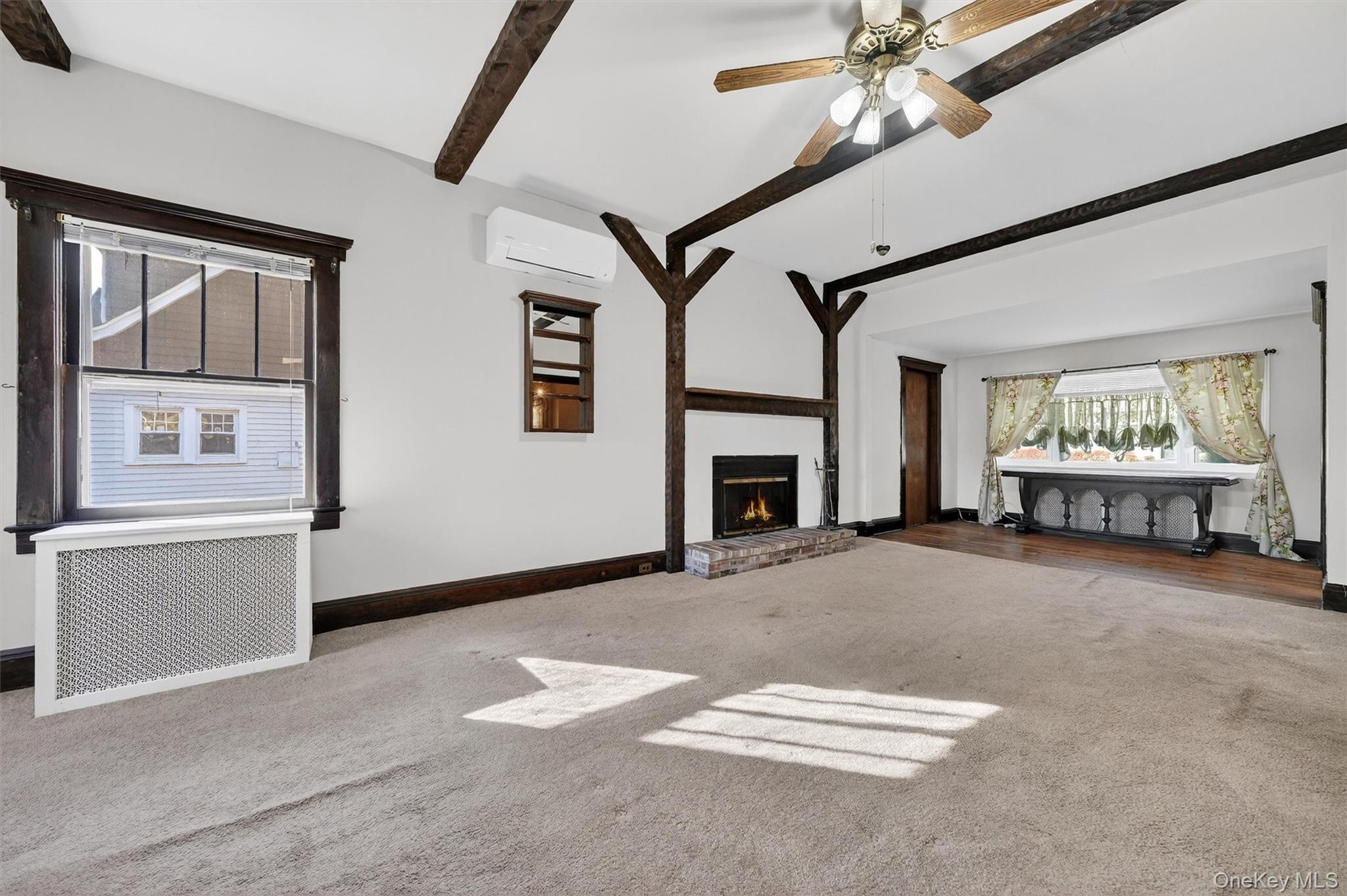 165 Wayne Avenue Suffern, NY 10901 - Photo 14 of 38 Unfurnished living room featuring beam ceiling, radiator heating unit, carpet floors, a brick fireplace, and an AC wall unit