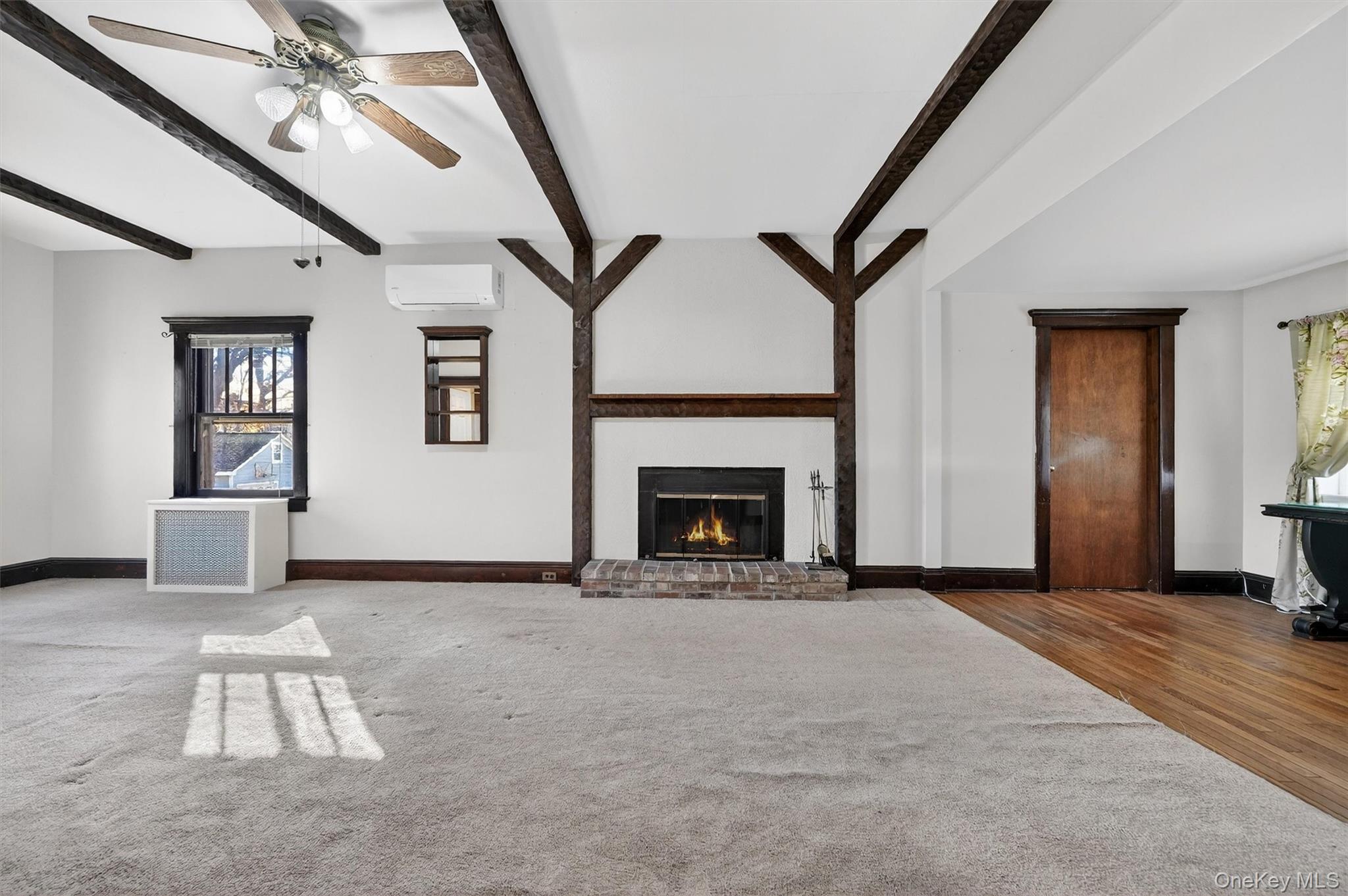165 Wayne Avenue Suffern, NY 10901 - Photo 2 of 38 Unfurnished living room with a brick fireplace, beamed ceiling, carpet flooring, healthy amount of natural light, and a ceiling fan
