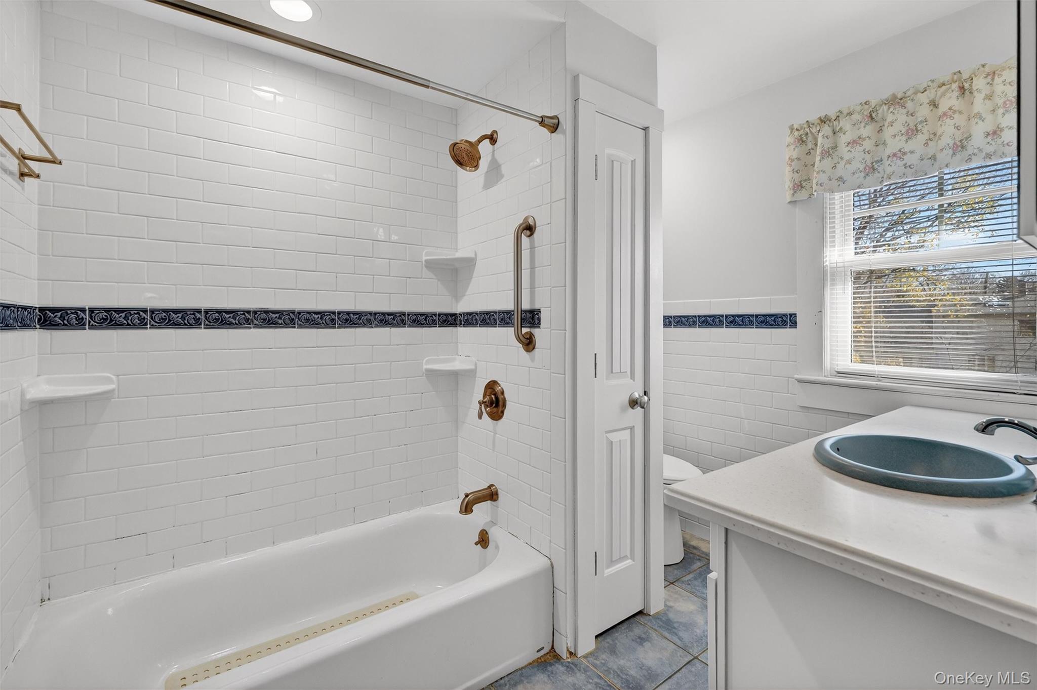 165 Wayne Avenue Suffern, NY 10901 - Photo 29 of 38 Bathroom with vanity, tile walls, bathtub / shower combination, dark tile patterned flooring, and a wainscoted wall