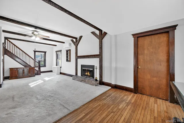 a view of an empty room with wooden floor fireplace and a window