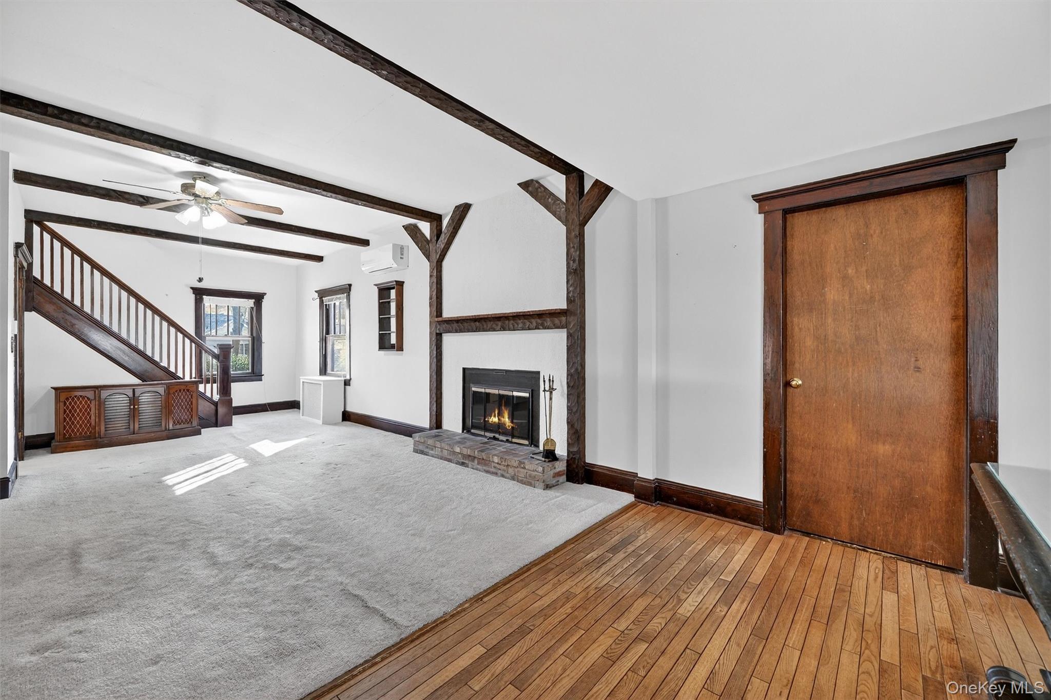 165 Wayne Avenue Suffern, NY 10901 - Photo 9 of 38 Unfurnished living room with beam ceiling, hardwood / wood-style flooring, ceiling fan, a brick fireplace, and carpet floors