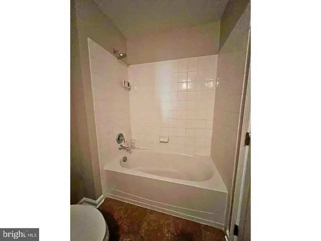 a bathroom with a granite countertop bathtub shower sink vanity and a toilet