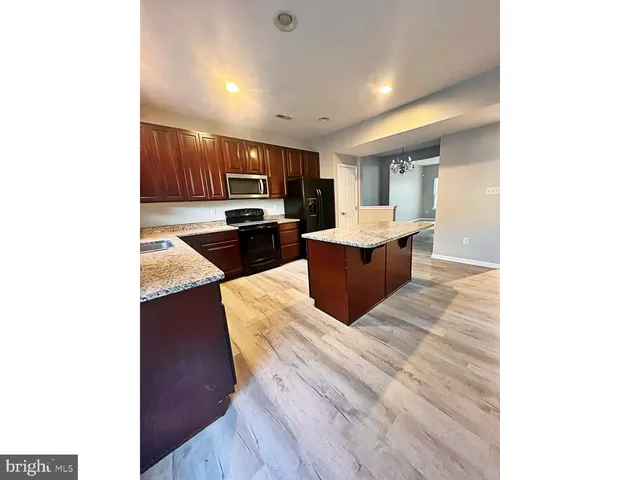 a living room with stainless steel appliances kitchen island granite countertop a sink and cabinets