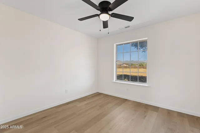 an empty room with a window and a ceiling fan