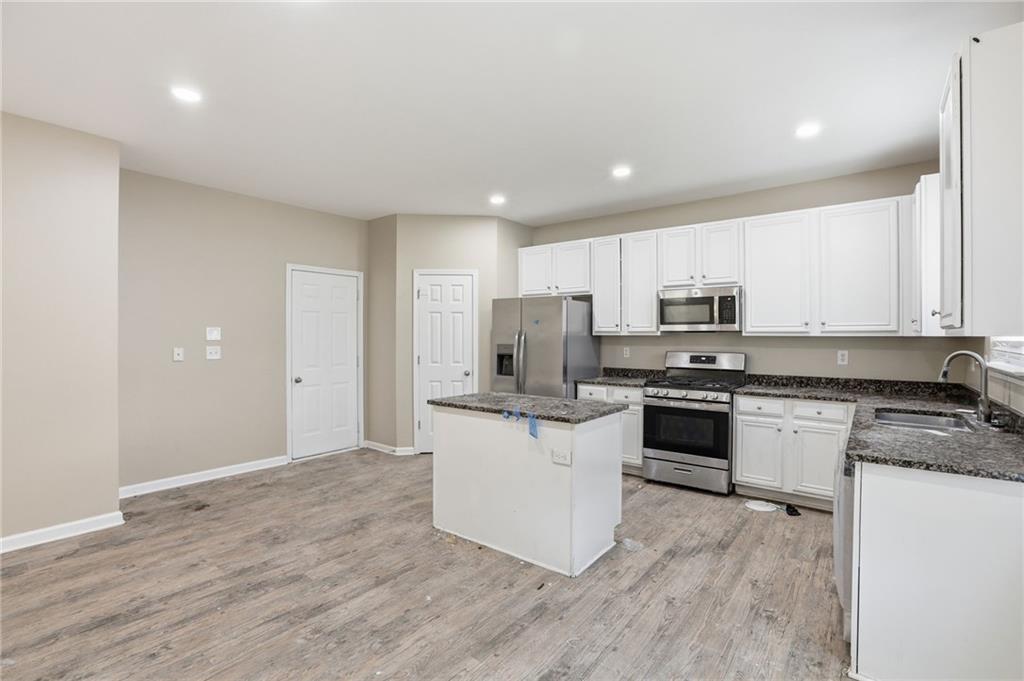 4968 Locherby Drive Fairburn, GA 30213 - Photo 15 of 39 a kitchen with stainless steel appliances granite countertop a stove top oven a sink dishwasher and a refrigerator with wooden floor