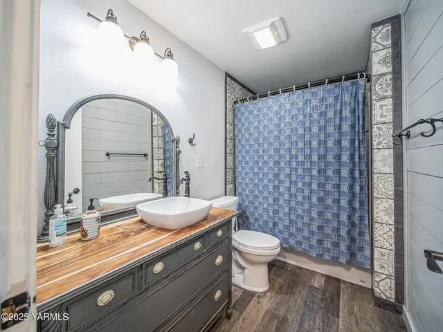a bathroom with a granite countertop toilet a sink and a mirror