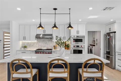 a kitchen with stainless steel appliances granite countertop a sink a stove a refrigerator and cabinets