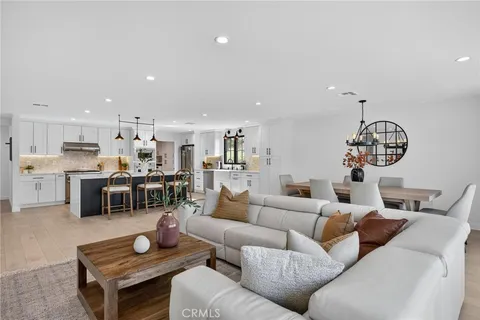 a living room with furniture kitchen view and a chandelier