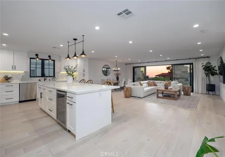 a open kitchen with stainless steel appliances kitchen island granite countertop a sink and white cabinets with wooden floor