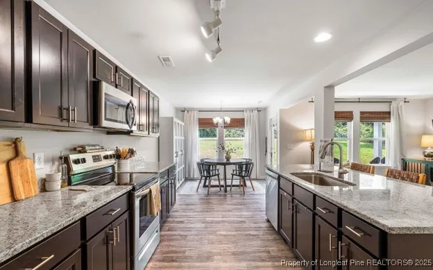 a kitchen with granite countertop lots of counter top space a sink stainless steel appliances and windows