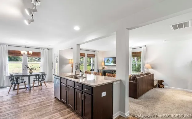a living room with stainless steel appliances granite countertop furniture wooden floor and a large window