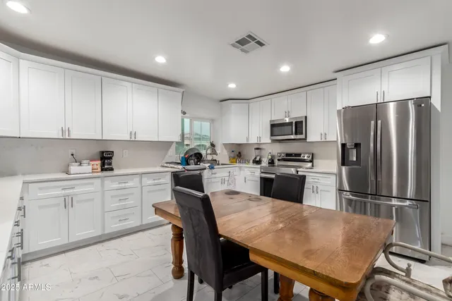 a kitchen with a refrigerator a stove a sink a dining table and chairs