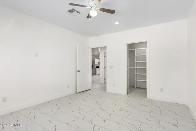 an empty room with a window and ceiling fan