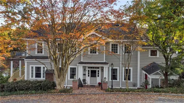 a view of a white house next to a large tree