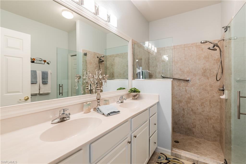14151 Fall Creek Court Naples, FL 34114 - Photo 14 of 35 a bathroom with a shower sink vanity granite and mirror