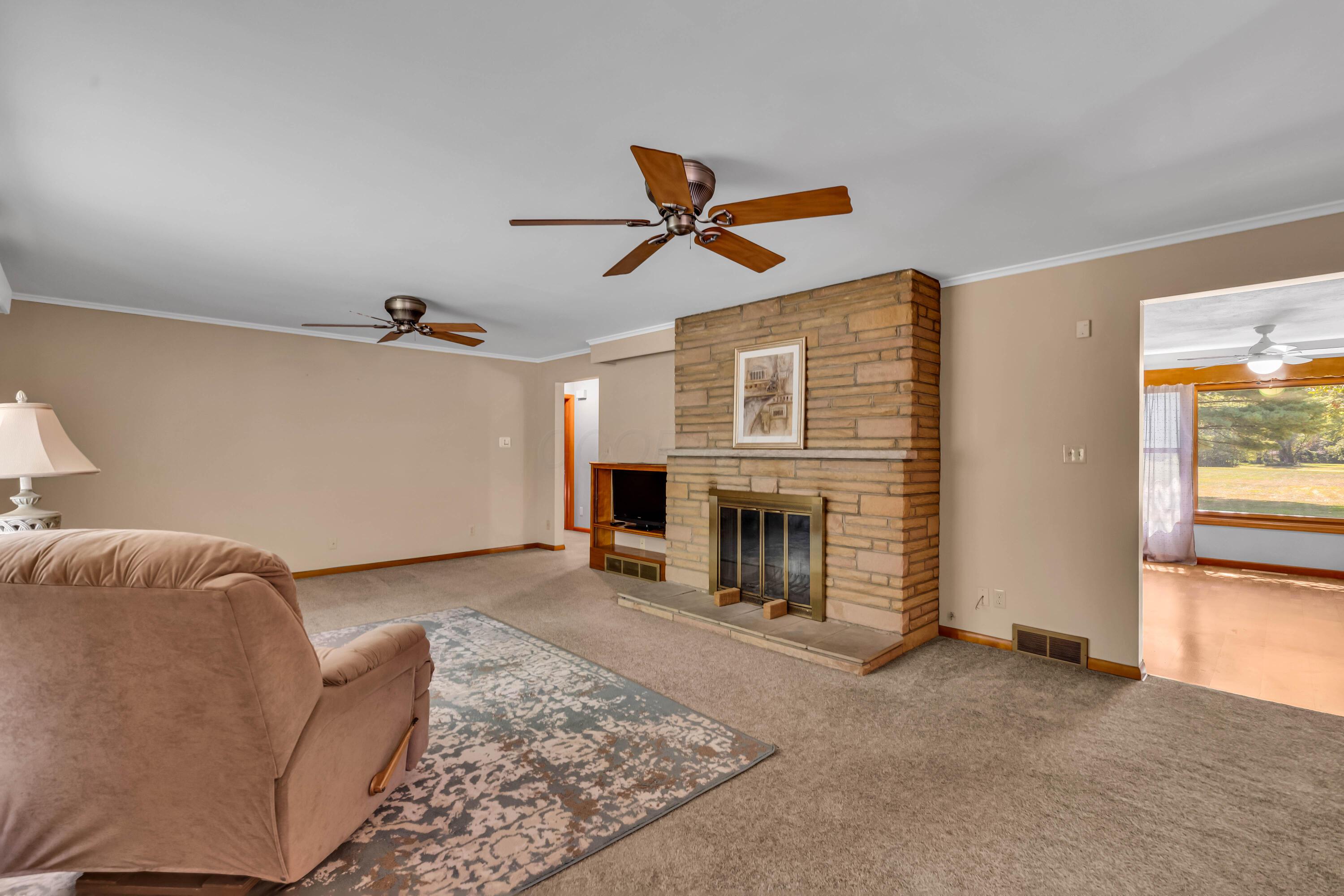 1213 East Cooke Road Columbus, OH 43224 - Photo 12 of 57 • Light sand carpet • Hardwood flooring under carpet • Tan painted walls • (2) ceiling fans • Stone fireplace with raised hearth • Crown molding