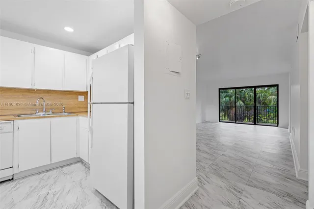 a view of a kitchen with a fridge and wooden floor