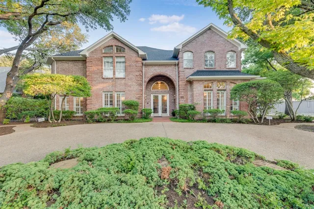a front view of a house with a garden and trees