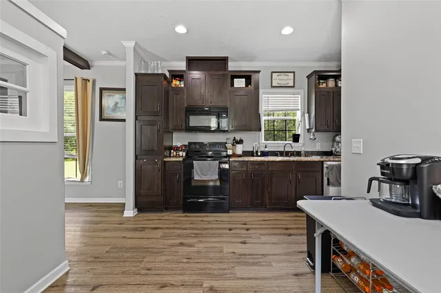 a kitchen with stainless steel appliances granite countertop a refrigerator a sink dishwasher a stove and a dining table with wooden floor