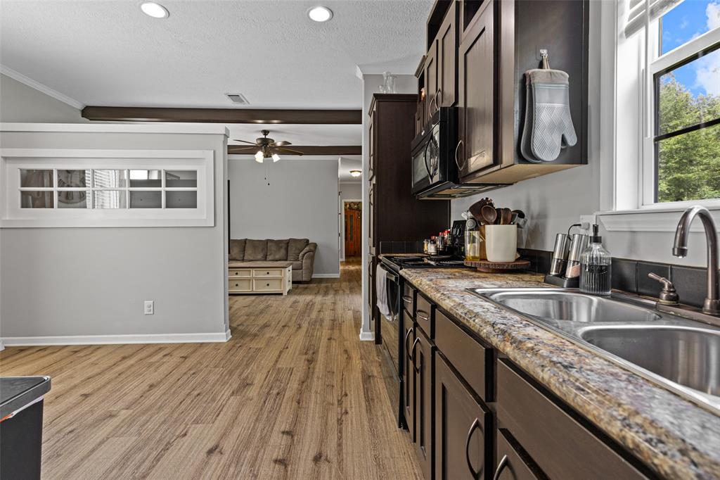 3489 Lotta Road Karnack, TX 75661 - Photo 15 of 39 a kitchen with stainless steel appliances granite countertop a sink a stove and a wooden floors